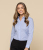 A button-up shirt in light blue, featuring a classic collar and long sleeves, worn by a smiling woman.