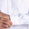 A men's white button-up shirt with a close-up of the cuff and buttons, featuring a logo.
