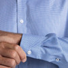 A blue check patterned button-up shirt with white buttons, showing a close-up of the sleeve and cuff.