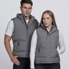 A grey puffer vest is worn by a man and a woman, both posing against a plain background. The vest has a logo.