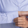 A blue and white check button-up shirt with long sleeves and a buttoned cuff. Features a logo on the chest.