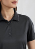 A women's short sleeve polo shirt in black with a textured pattern and a button-up collar. It features a logo.