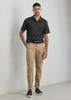 A black short sleeve polo shirt with a subtle pattern, paired with beige trousers and sneakers. The model stands confidently.