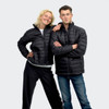 A black puffer jacket is worn by both a woman and a man, posing together with smiles. The jackets feature a branding logo.