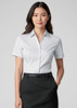 A button-up shirt in white, featuring a short sleeve design, worn with a black skirt. The shirt has a logo.