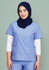A woman wearing a light blue scrub top with two pockets, layered over a white long-sleeve shirt, and a navy hijab.