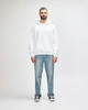 A white hooded sweatshirt worn by a young man, paired with black jeans and sneakers. The sweatshirt features a logo.