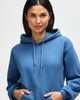 A blue hooded sweatshirt with a female model showcasing the product, featuring a logo on the fabric.