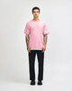 A heavyweight cotton unisex T-shirt in pink, paired with light blue jeans and black sneakers, displayed on a male model.