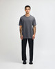 A unisex heavyweight cotton t-shirt in grey, paired with light blue jeans and black sneakers, featuring a logo.