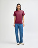 A unisex heavyweight cotton t-shirt in maroon, worn with light blue baggy jeans and black sneakers, featuring a logo.