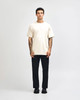 A model wearing a lightweight off-white unisex t-shirt paired with blue jeans and white sneakers, featuring a logo.