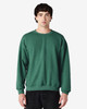 A green Gildan Heavy Blend adult crewneck sweatshirt displayed on a model, featuring long sleeves and a casual fit.