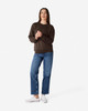 A woman wearing a dark brown Gildan Heavy Blend crewneck sweatshirt and blue jeans, standing on a neutral background.