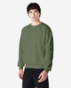 A man wearing a green crewneck sweatshirt, featuring long sleeves and a relaxed fit. The sweatshirt has a logo.