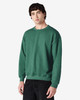 A green crewneck sweatshirt on a model, featuring long sleeves and a relaxed fit. The product has a logo.