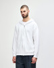 A white Gildan Heavy Blend adult full zip hooded sweatshirt is displayed on a model. The sweatshirt features a hood and a relaxed fit.