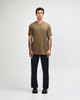 A model wearing a unisex short sleeve T-shirt in olive green, paired with black cargo pants and sneakers.