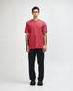 A unisex CVC short sleeve t-shirt in red, paired with black cargo pants. The model displays a casual pose.