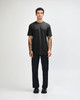 A black unisex short sleeve t-shirt worn with light blue baggy jeans and black sneakers. The model poses against a plain background.