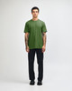 A unisex short sleeve T-shirt in green, worn with black cargo pants. The model is standing with a relaxed pose.