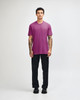 A unisex short sleeve T-shirt in vibrant pink, paired with relaxed black pants and a casual stance.