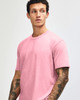 A unisex short sleeve T-shirt in pink, featuring a simple design and a logo.
