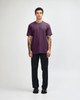 A unisex short sleeve T-shirt in a deep purple colour, paired with black cargo pants, featuring a logo.