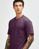 A unisex short sleeve t-shirt in a deep purple colour, displayed by a model. Features a plain design with a logo.