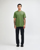 A model wearing a green unisex CVC short sleeve T-shirt paired with black cargo pants and sneakers.