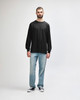 A long sleeve t-shirt in dark grey worn by a model, paired with black trousers and sneakers.