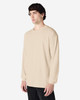 A beige long sleeve T-shirt on a model, featuring a simple design and a logo on the garment.