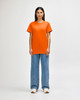 An orange Gildan Heavy Cotton adult T-shirt worn by a standing male model, paired with black jeans and sneakers.