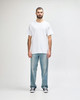 A man in a plain white Gildan Heavy Cotton T-shirt paired with blue jeans and black shoes, standing against a neutral background.