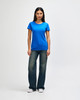 A blue Gildan Heavy Cotton Ladies' T-Shirt displayed on a model, paired with denim jeans and white sneakers.