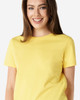 A yellow Gildan Heavy Cotton Ladies' T-Shirt displayed on a model, featuring a simple design and a logo.