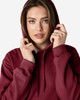 A woman models a burgundy Gildan Softstyle adult hooded sweatshirt with a drawstring hood and a subtle logo.