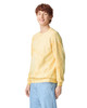 A yellow tie-dye crewneck sweatshirt on a model, featuring a relaxed fit and long sleeves. It has a logo.
