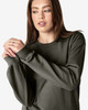 A woman wearing a dark green Gildan Softstyle adult sweatshirt, with long sleeves and a relaxed fit.