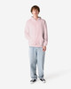 A unisex hooded sweatshirt in pink, featuring a front pocket and a logo, worn with light blue jeans.