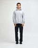 A unisex grey hooded sweatshirt with a kangaroo pocket, paired with light blue jeans and black sneakers.