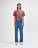 A woman's boxy t-shirt in rose, paired with light blue cargo jeans, featuring a logo on the shirt.