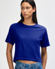 A woman wearing a blue boxy t-shirt, styled with denim shorts, featuring a branded logo.