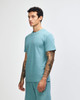 A unisex pique mockneck t-shirt in a teal colour, featuring a slight side profile view. The shirt has a logo.