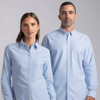 Two models wearing light blue button-up shirts. The shirts feature collars and front pockets, along with branding.
