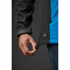 A close-up of a hand adjusting the hem of a blue and black softshell jacket, featuring a logo on the side.
