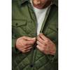 A man in a green quilted jacket adjusts the zipper, revealing a grey top underneath. The jacket features snap buttons and a logo.
