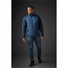 A men's hybrid jacket in navy blue, featuring a padded front and textured sleeves. The model is wearing jeans and black shoes.