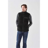 A black men's Sherpa fleece vest features a zip front and a pocket, worn over a long-sleeve top and jeans.