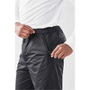 Men's Olympia Rain Pant in black, featuring an elastic waistband and a side zip pocket, with a person wearing them.
